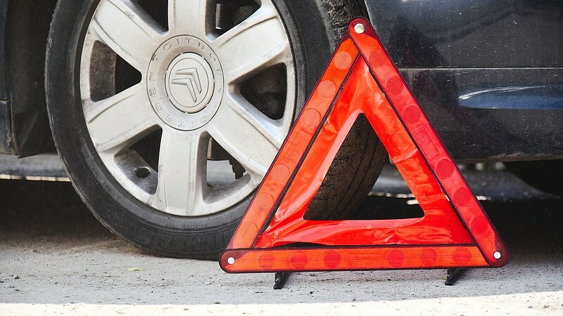 знак в виде треугольника стоит возле автомобильного колеса
